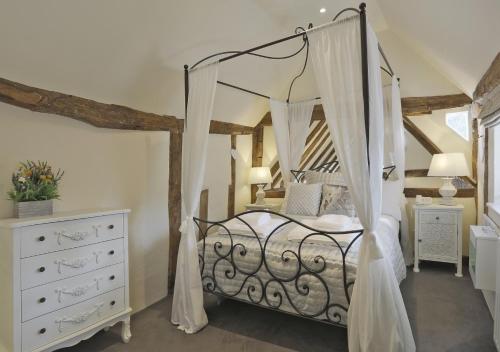 a bedroom with a canopy bed and a white dresser at Lady Cottage in Lavenham