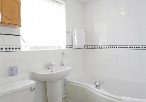 a white bathroom with a sink and a bath tub at Hollyhocks in Bawdsey