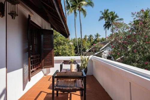 a balcony with a table and chairs and palm trees at Sanctuary Hotel Luang Prabang in Luang Prabang