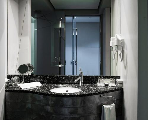 a bathroom with a sink and a large mirror at Golden Tulip Zira Belgrade in Belgrade