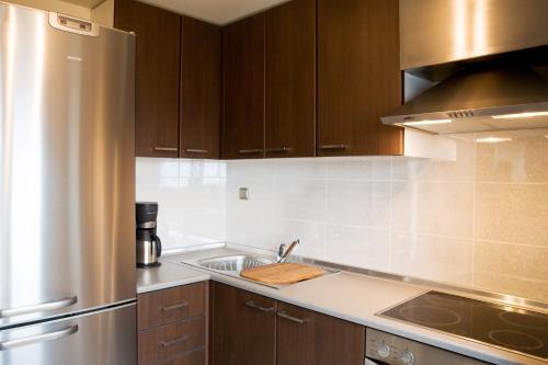 a kitchen with wooden cabinets and a stainless steel refrigerator at Melon Suites in Thessaloniki