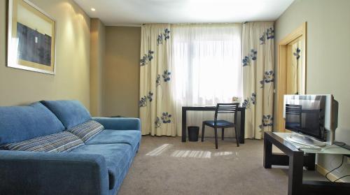 sala de estar con sofá azul y TV en Blu Hotel Pamplona, en Imárcoain