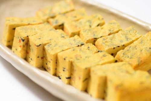 a white plate of cheese crackers on a table at Pacific Hotel Shiroishi in Shiroishi