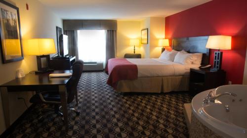 a hotel room with a bed and a bathroom with a tub at Holiday Inn Saint Louis-Fairview Heights by IHG in Fairview Heights