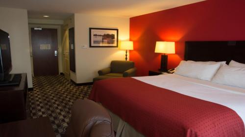 a hotel room with a large bed and a chair at Holiday Inn Saint Louis-Fairview Heights by IHG in Fairview Heights