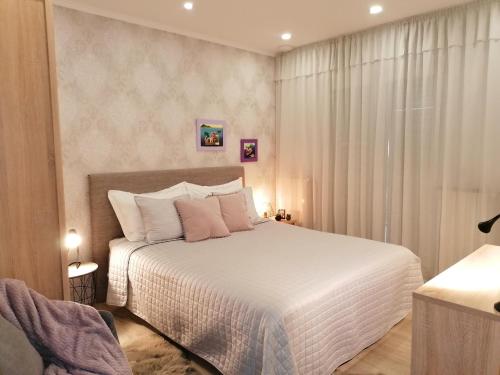 a bedroom with a bed with white sheets and pink pillows at Apartments Iris in Hvar