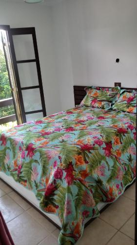 a bed with a colorful comforter on it with at Recanto J&R in Angra dos Reis