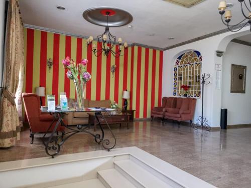 a lobby with a table and chairs and red and white stripes at Hotel Plaza Escribano in Moguer