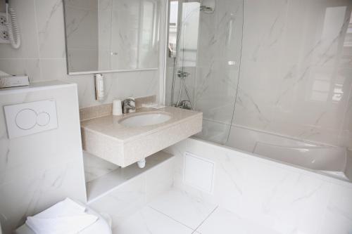 a white bathroom with a sink and a shower at Arcadie Montparnasse in Paris