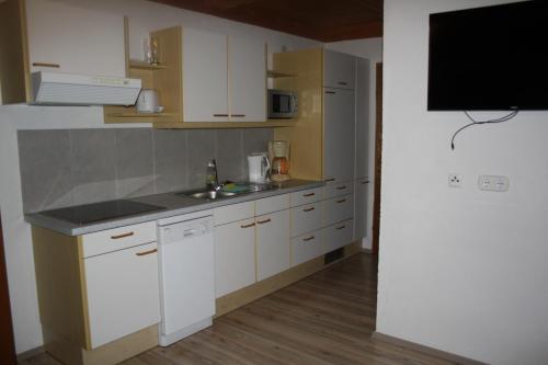 a kitchen with white cabinets and a sink and a tv at Ferienwohnung Fam. Bidner in Flattach
