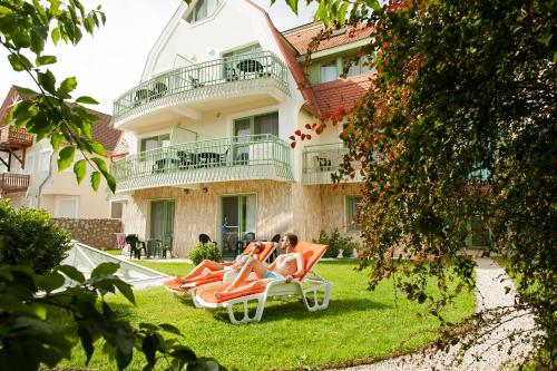 two women sitting on lawn chairs in front of a building at Holiday Club Apartman Hotel in Hévíz
