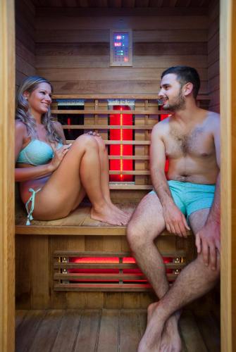 a man and woman sitting on a bench in a sauna at Holiday Club Apartman Hotel in Hévíz