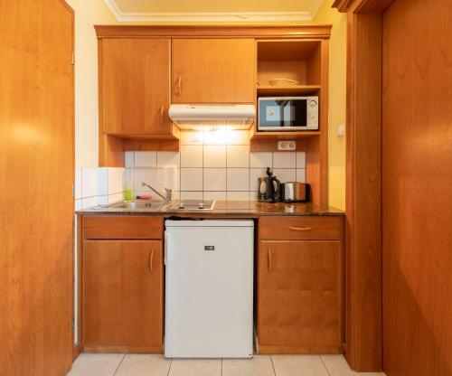 a kitchen with a white refrigerator and a microwave at Holiday Club Apartman Hotel in Hévíz