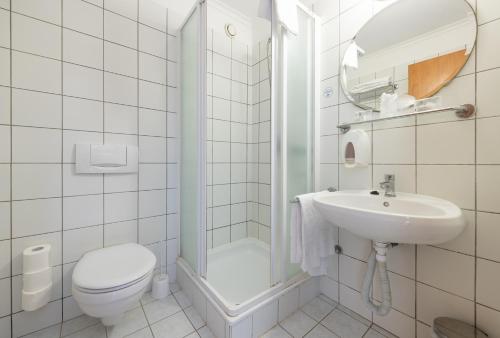 a white bathroom with a toilet and a sink at Holiday Club Apartman Hotel in Hévíz