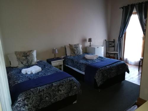 a bedroom with two beds with blue sheets and a window at Bougain Villa Guesthouse in Winburg
