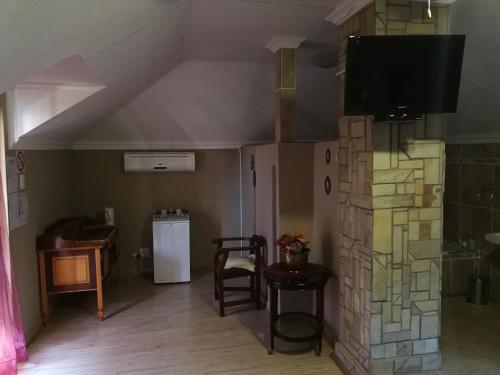 a living room with a tv and a stone wall at Bougain Villa Guesthouse in Winburg