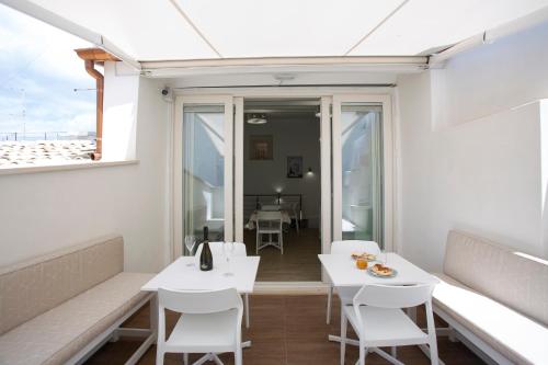 a room with white tables and chairs and a window at Vento di Sicilia in Siracusa