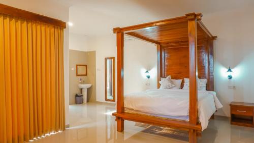a bedroom with a wooden canopy bed with white sheets at Sunburn Villa in Nusa Dua