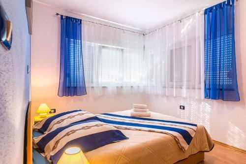 a bedroom with a bed with blue curtains and a window at Apartman Nada *** in Medulin