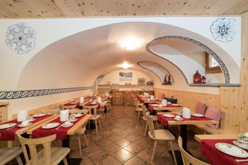 ein Restaurant mit Holztischen und -stühlen und einem Torbogen in der Unterkunft Meublè Garnì Della Contea in Bormio