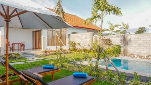 Sunburn Villa في نوسا دوا: حديقة خلفية مع حمام سباحة ومنزل