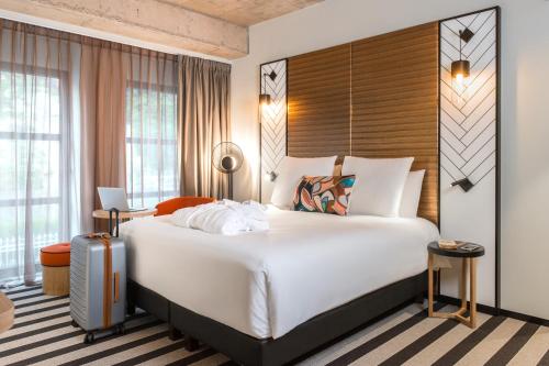 une chambre d'hôtel avec un grand lit et une valise dans l'établissement Mercure Luxembourg Off Kirchberg, à Luxembourg