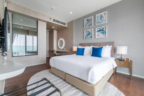 a bedroom with a large bed with blue pillows at Mövenpick Residence/Beach Access/2BR/Luxury Stay in Na Jomtien