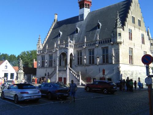 un gran edificio con coches estacionados en un estacionamiento en Gasthof Maerlant, en Damme