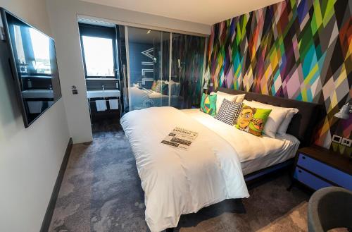 um quarto com uma cama grande e uma parede colorida em Village Hotel Basingstoke em Basingstoke