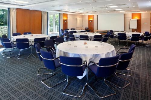 a conference room with tables and chairs and a whiteboard at Holiday Inn Guildford by IHG in Guildford