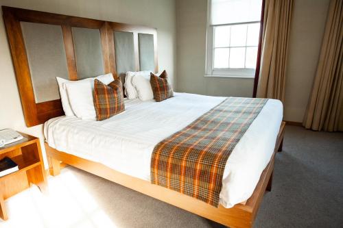a bedroom with a large bed with a plaid blanket at Berwick Manor Hotel in Rainham