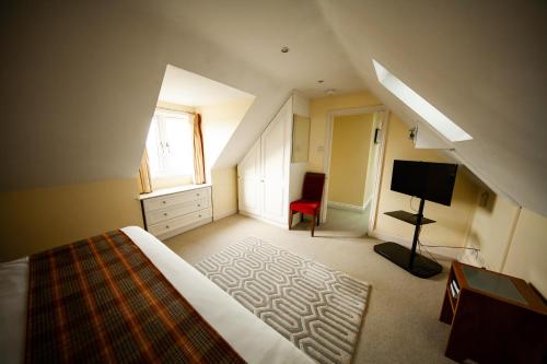 a attic bedroom with a bed and a television at Berwick Manor Hotel in Rainham