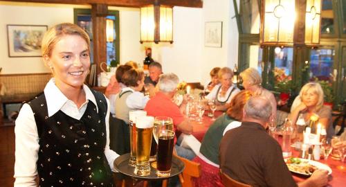 Una donna che tiene un vassoio di birra in un ristorante di Hotel Gasthof Tirolerwirt a Bischofshofen