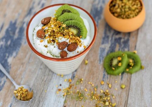 a bowl of yogurt with a kiwi and nuts on it at ibis Styles Le Puy en Velay in Le Puy en Velay