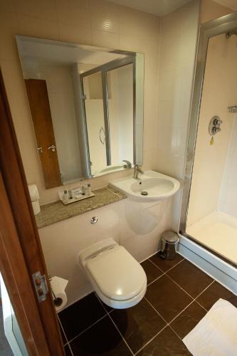 a bathroom with a toilet and a sink and a mirror at Berwick Manor Hotel in Rainham