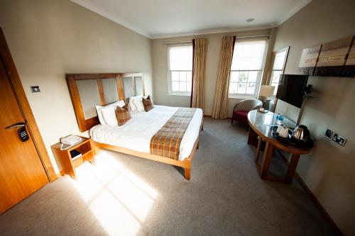a hotel room with a bed and a desk at Berwick Manor Hotel in Rainham