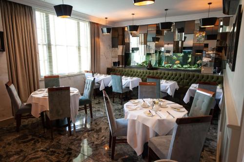 a dining room with white tables and chairs and a window at Berwick Manor Hotel in Rainham