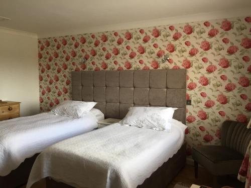 2 Betten in einem Zimmer mit Blumen an der Wand in der Unterkunft Ingledene Room Only in Pickering