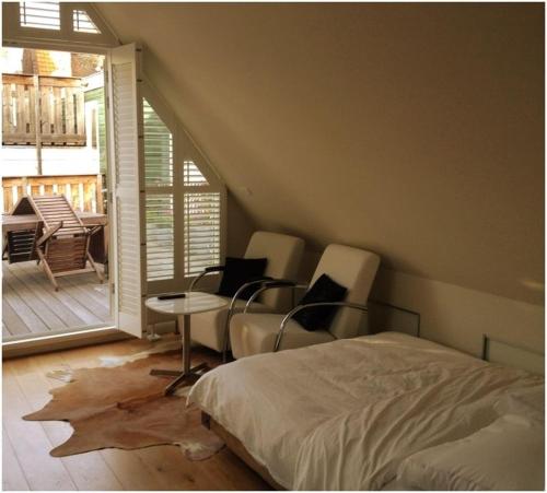 a bedroom with a bed and chairs and a porch at Prince On The Roof in Amsterdam