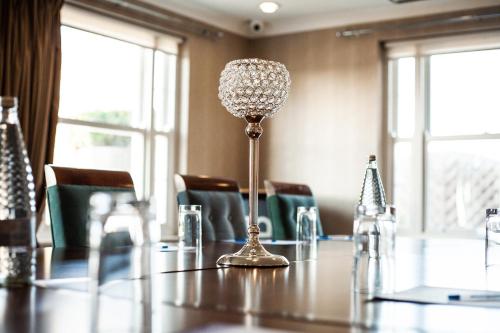 a table with a lamp in a room with chairs at Berwick Manor Hotel in Rainham
