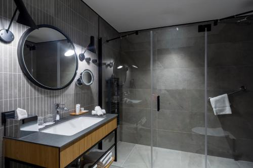 a bathroom with a shower and a sink and a mirror at Radisson Hotel & Apartments Gdansk in Gdańsk