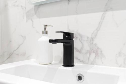 La salle de bains est pourvue d'un lavabo avec un robinet noir. dans l'établissement SLEEPOO - Villa Boheme 7, à Trouville-sur-Mer