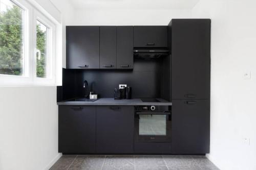 une cuisine avec des armoires noires et une fenêtre dans l'établissement SLEEPOO - Villa Boheme 7, à Trouville-sur-Mer