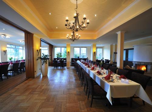 a dining room with tables and chairs and a chandelier at Akzent Hotel Cordes & Restaurant am Rosengarten in Sottorf