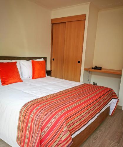 a bedroom with a large bed with orange pillows at Apart Hotel Viva Providencia in Santiago