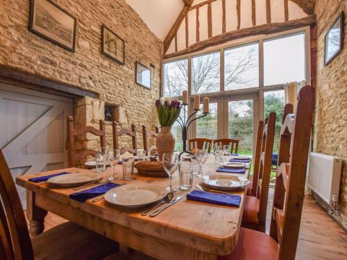 uma sala de jantar com uma mesa de madeira com copos em Butts Farm em Cirencester