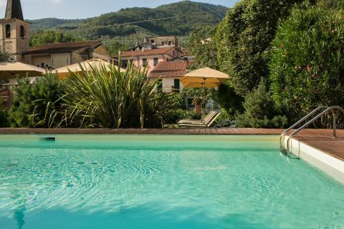 a large blue swimming pool in a yard with houses at Relais Del Maro in Borgomaro