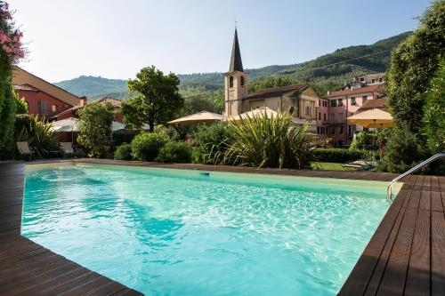 a large swimming pool with a church in the background at Relais Del Maro in Borgomaro