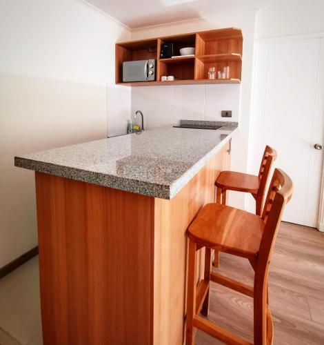 a kitchen with a counter and a wooden stool at Apart Hotel Viva Providencia in Santiago