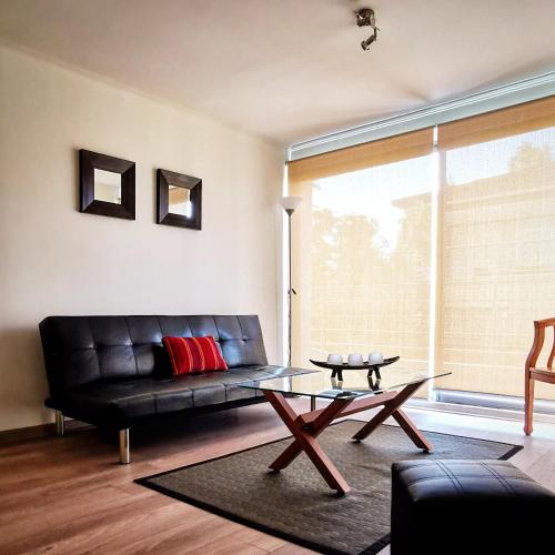 a living room with a black leather couch and a table at Apart Hotel Viva Providencia in Santiago